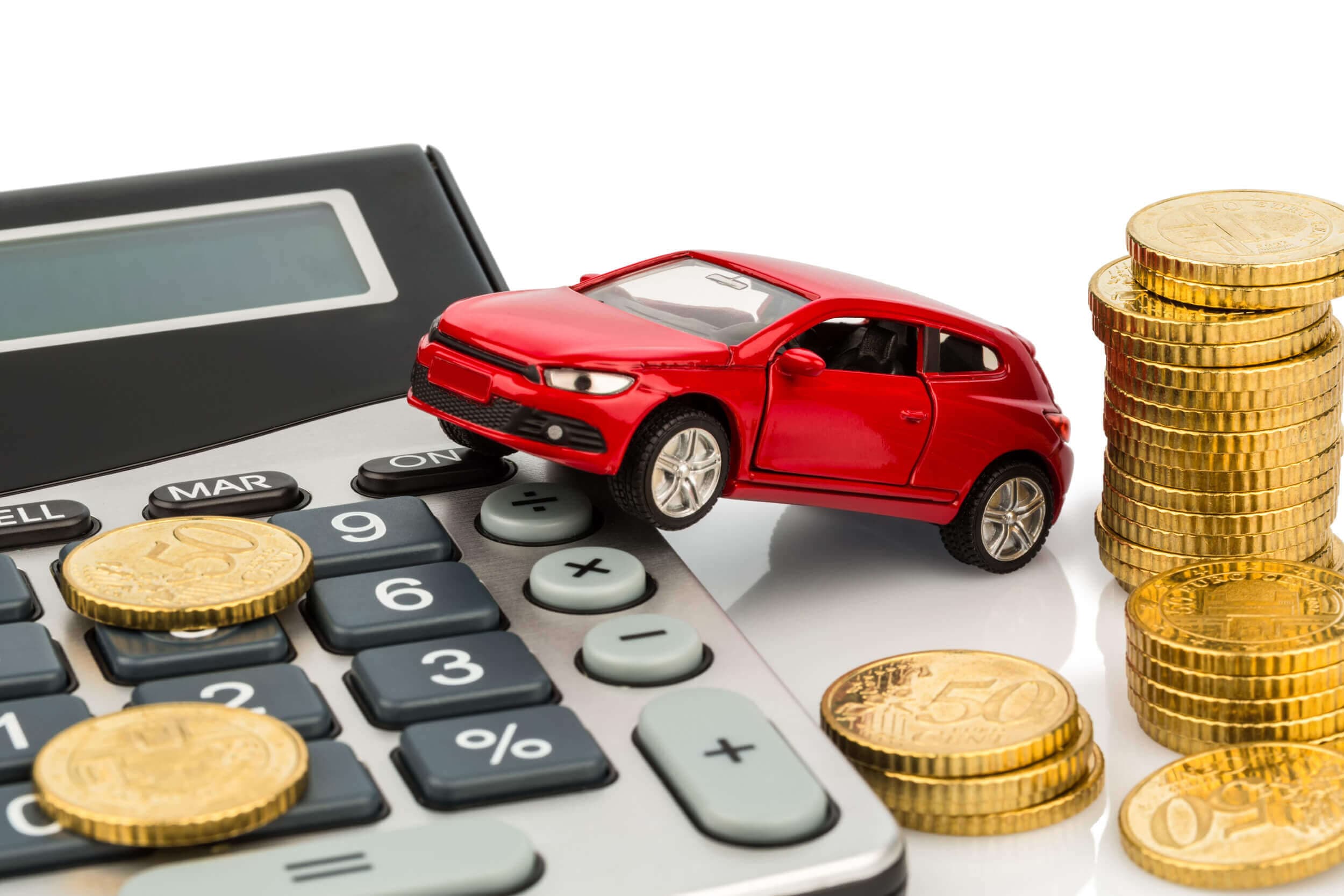 red car perched on calculator with coins scattered around it